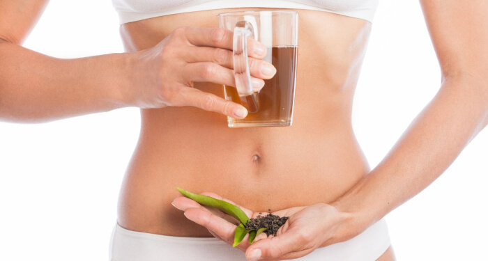 Person hält einen Tee und Kräuter in der Hand detox-tee-zum-abnehmen